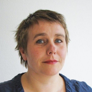 Eine Frau blickt lächelnd in die Kamera.
