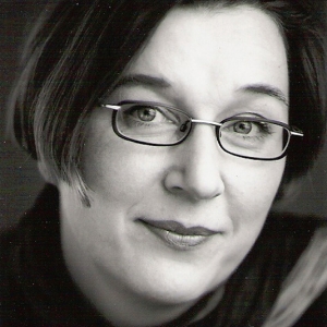 Eine Frau blickt lächelnd in die Kamera. Das Bild ist schwarz-weiß.
