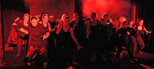 Viele Personen stehen im Pulk. Sie sind in rotes Licht und Nebel getaucht.