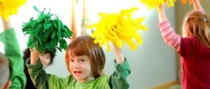 Ein Kind tanzt mit Pompoms. Im Hintergrund sind weitere Kinder zu sehen.