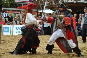 Zwei als Piraten verkleidete Personen kämpfen miteinander. Ein Publikum sieht ihnen zu.