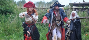 Drei als Piraten verkleidete Personen stehen vor einer Wiese.