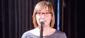 Eine Frau steht am Mikrofon.