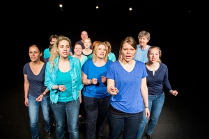 Eine Gruppe von Personen geht im Pulk gemeinsam nach vorne. Alle tragen blaue T-Shirts.