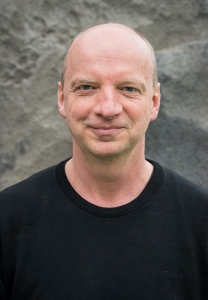 Ein Mann blickt lächelnd in die Kamera.