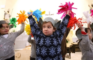 Kinder tanzen mit bunten Pompoms. Sie tragen selbstgebastelte Mäuseohren auf dem Kopf.