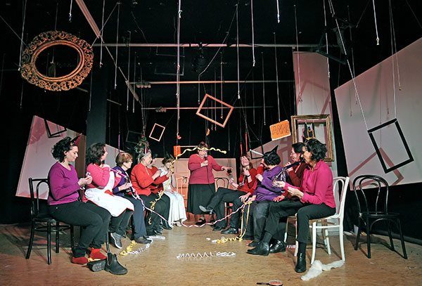 TPZ-Hildesheim-Mitspielen-Mitmachen-bei-Theater-Alt-und-Jung Viele Frauen sitzen sich in zwei Reihen gegenüber. Sie pusten Luftschlangen. Am Ende der beiden Reihen steht eine Frau mit einem Mikrofon in der Hand.
