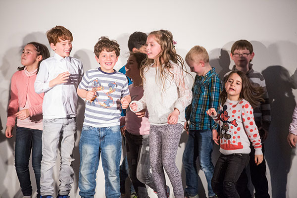 Grundschule-TPZ-Hildesheim-Bewegung-Ausdruck-GS Kinder tanzen zusammen auf einer Bühne.