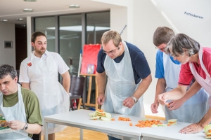 Mehrere Personen stapeln Kohlrabi und Möhrenscheiben aufeinander.