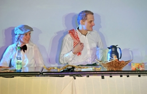 Ein Mann und eine Frau stehen hinter einem Frühstücksbuffet. Sie tragen weiße Hemden. Der Mann hat sich ein Geschirrtuch über die Schulter geworfen.