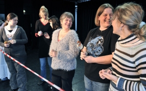 Mehrere Personen stehen hinter einem Absperrband und lachen.