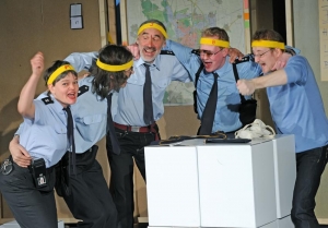 Fünf Personen in Polizeiuniformen halten sich an den Schultern und jubeln. Sie tragen gelbe Stirnbänder auf dem Kopf.