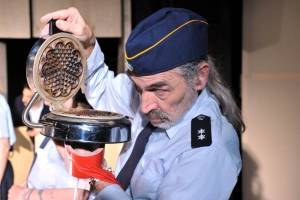In Mann in blauer Uniform inspiziert ein geöffnetes Waffeleisen. Er hält eine Rolle rotes Absperrband in der Hand.