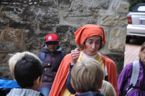 Eine Frau im Kostüm spricht mit einer Gruppe von Schulkindern.
