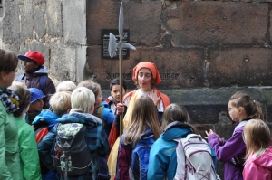 Eine Frau im Kostüm gibt eine Stadtführung für Kinder.
