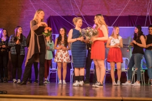 Zwei Personen vergeben Blumen an die Teilnehmenden eines Theaterstücks.
