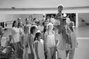 Kinder und Jugendliche stehen im Pulk zusammen. Ein Junge trägt ein Mädchen auf den Schultern. Alle tragen helle Kleidung.