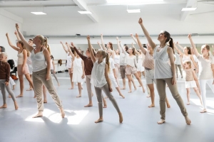 Viele Kinder und Jugendliche zeigen gemeinsam eine Tanzperformance. Sie strecken den rechten Arm nach oben und folgen mit dem Körper.