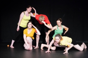 Eine Gruppe von Menschen führt einen Tanz vor. Einige Personen haben einen Apfel in der Hand.