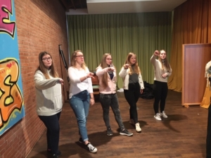 Fünf junge Frauen stehen in einer Reihe. Sie recken den rechten Daumen nach unten.