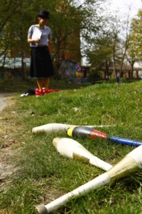 Mehrere Kegel liegen auf einer grünen Wiese. Im Hintergrund steht eine Person mit einem Zylinder.