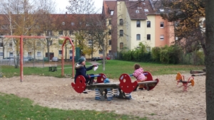 Auf einem Spielplatz schaukelt eine Mutter mit ihrem Kind.