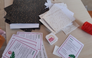 Rezepte für Plätzchen liegen auf einem Tisch. Daneben liegen schwarze und weiße Papiertüten. Die Tüten sind mit Sternen verziert.