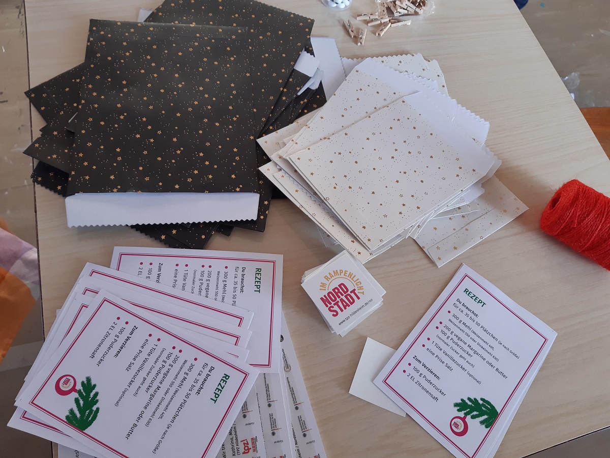 Rezepte für Plätzchen liegen auf einem Tisch. Daneben liegen schwarze und weiße Papiertüten. Die Tüten sind mit Sternen verziert.