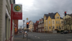 Eine Straße in Hildesheim. Links befindet sich eine Bushaltestelle mit dem Namen "Martin-Luther-Straße". Rechts befindet sich ein gelbes Gebäude und eine Ampel.