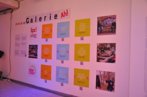 Fotos und Zitate hängen aufgereiht an einer Wand. Darüber steht der Schriftzug: "Galerie Ah!"
