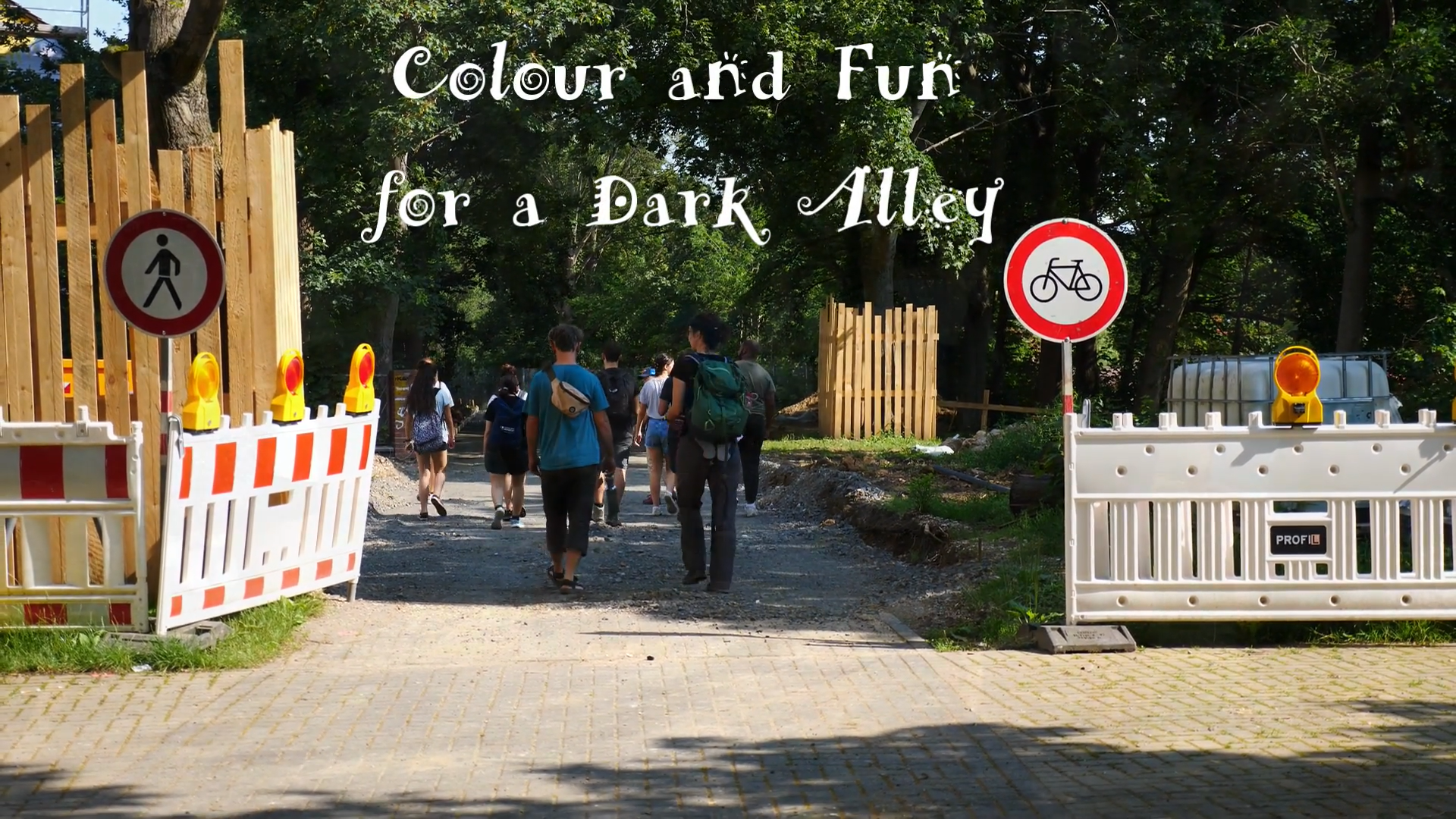 Menschen gehen einen Weg entlang. Links und rechts befindet sich eine Baustelle. Über dem Bild steht in weißer Schrift: "Colour and Fun for a Dark Alley".