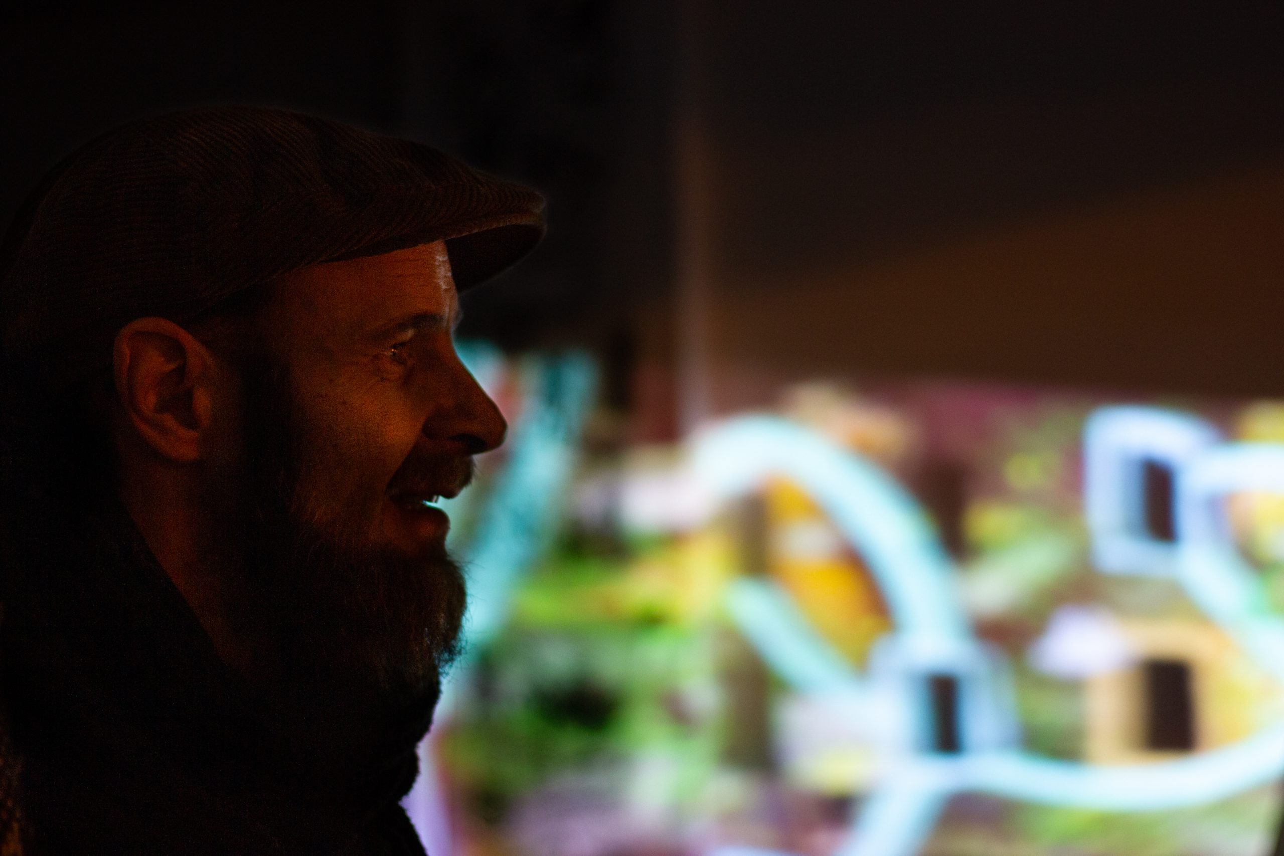 Ein Mann ist aus der Seitenansicht zu sehen. Hinter ihm befinden sich bunte Lichter.