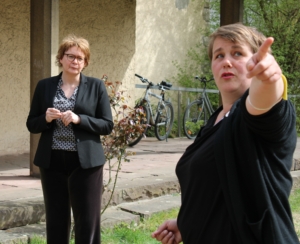 Die Sozialministerin Daniela Behrens steht auf einer Wiese. Sie blickt zur Geschäftsführerin vom TPZ, Katrin Löwensprung. Diese zeigt in eine Richtung oberhalb der Kamera.