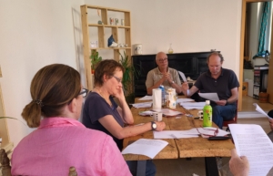 Mehrere Personen schreiben und lesen an einem Tisch.