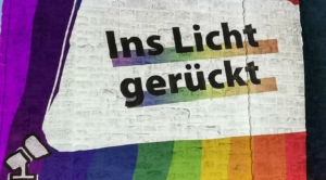 Vor einem bunten Hintergrund steht die Aufschrift "Ins Licht gerückt".