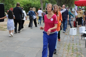 Viele Menschen tanzen in einer Reihe auf der Straße. Sie tragen Kopfhörer.