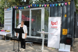 Die Geschäftsführerin vom TPZ steht vor dem Schiffscontainer und hält eine Rede.