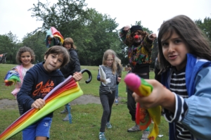 Kinder und Erwachsene laufen mit bunten Regenschirmen auf die Kamera zu.