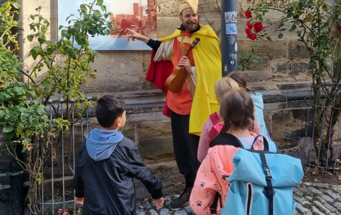 Ein Mann in einem mittelalterlichen Kostüm erklärt Kindern die Hildesheimer Stadtgeschichte.