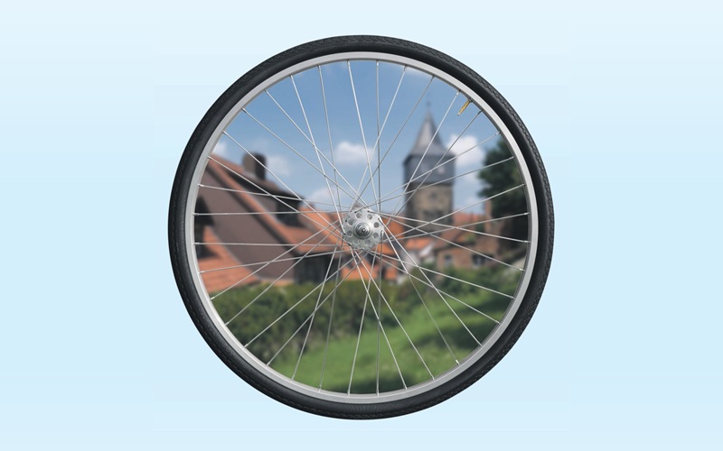 Der Blick durch die Speichen eines Rads von einem Fahrrad. Dahinter ist der Kehrwiederturm in Hildesheim zu erkennen.