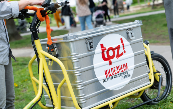 Ein Lastenfahrrad mit TPZ-Aufkleber steht auf einer Wiese.
