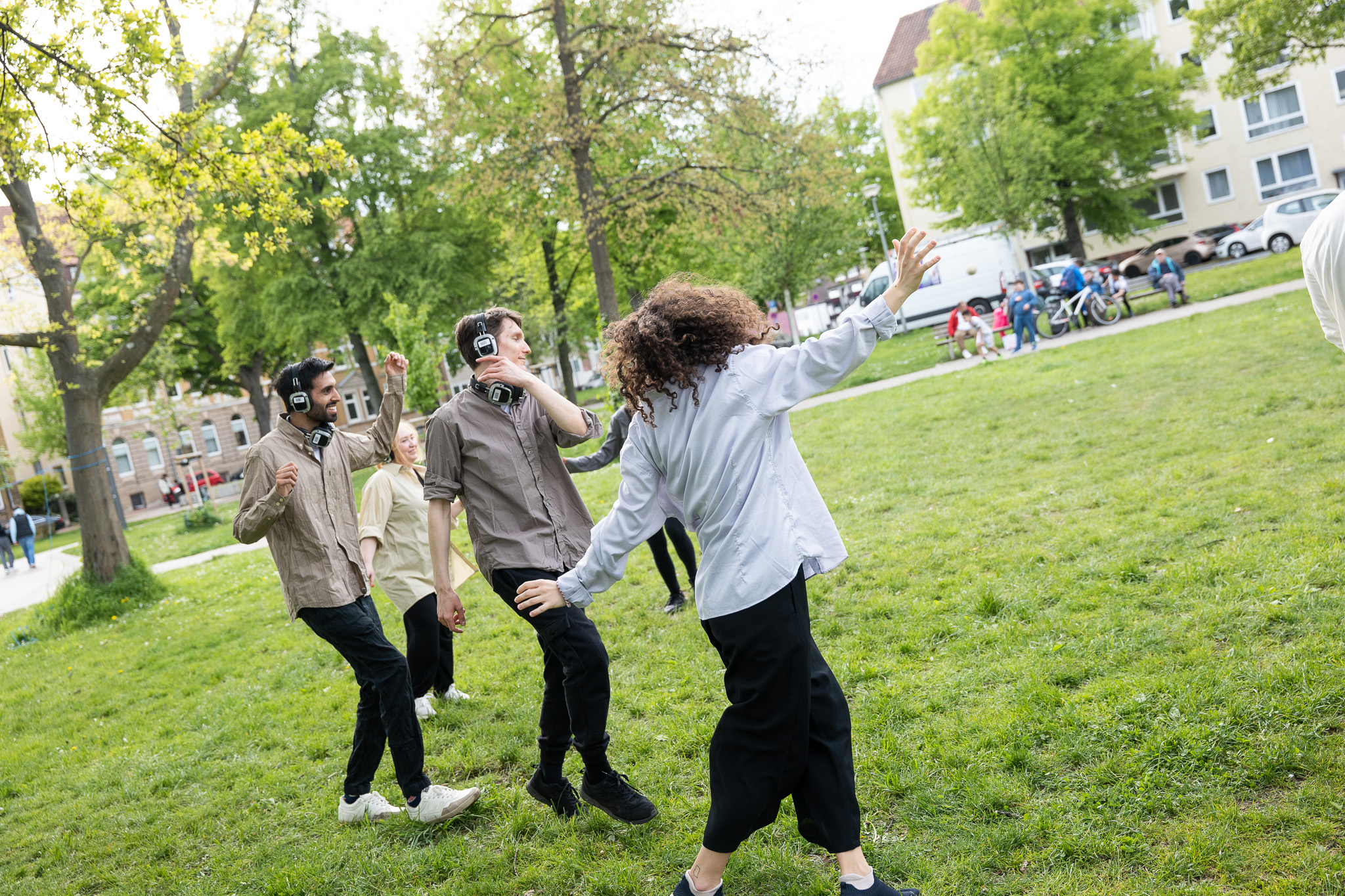 Menschen tanzen mit Kopfhörern auf den Ohren durch den Park.