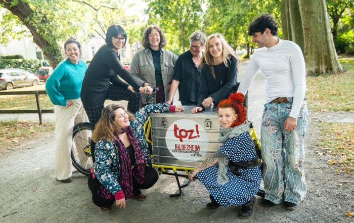 Acht Personen stehen um ein gelbes Lastenfahrrad herum. Auf dem Fahrrad befindet sich das rote Logo vom TPZ.