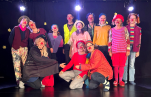 Viele Menschen stehen in einem Pulk zusammen auf einer Bühne. Sie sind als Clowns verkleidet.