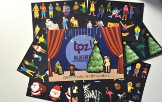 Eine Weihnachtspostkarte vom TPZ liegt auf einem Tisch. Rings herum liegen viele kleine Figuren und Tiere zum Ausschneiden.