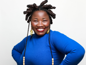 Oumou lacht in die Kamera vor einem weißen Hintergrund